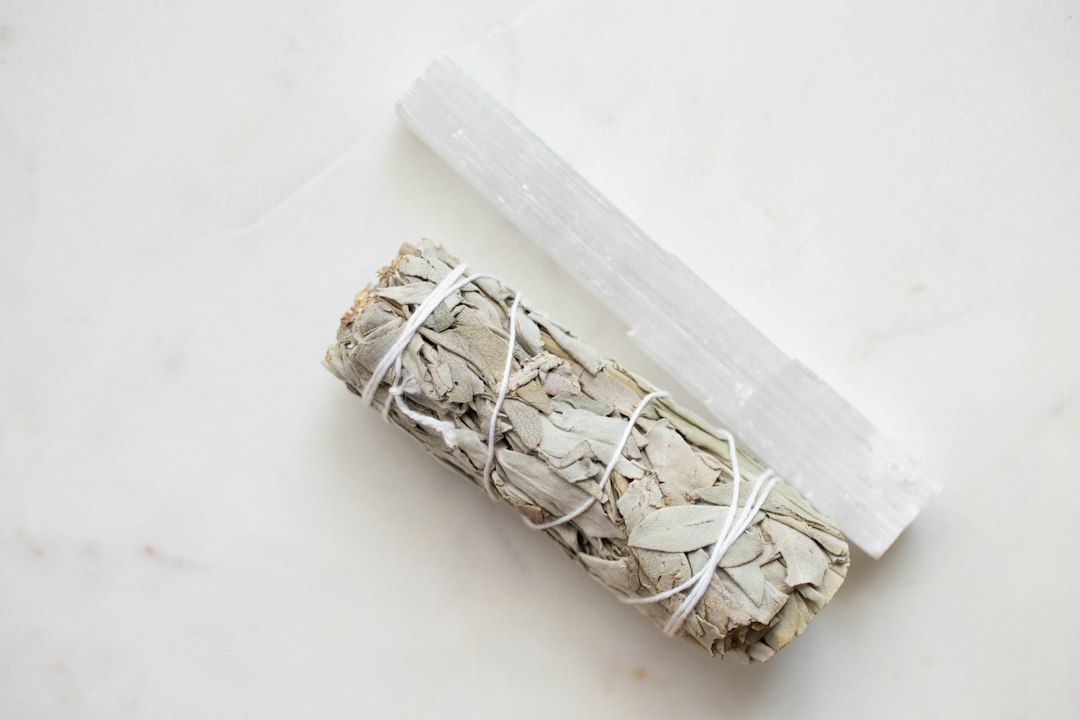 Selenite wand laid next to a white sage smudge bundle